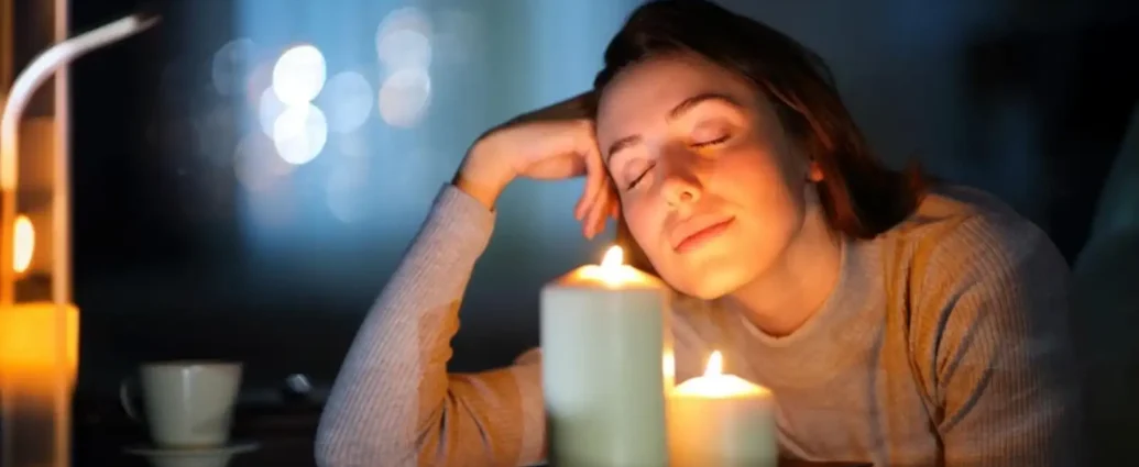 Woman relaxing beside lit candles creating a warm and calming fragrance ambiance