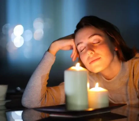 Woman relaxing beside lit candles creating a warm and calming fragrance ambiance