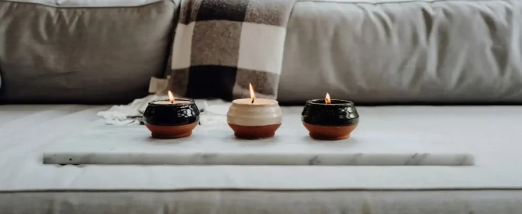 Three small candles burning on a marble tray in a cozy living room setting