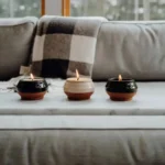 Three small candles burning on a marble tray in a cozy living room setting
