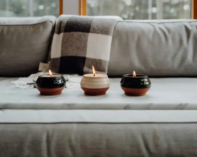 Three small candles burning on a marble tray in a cozy living room setting